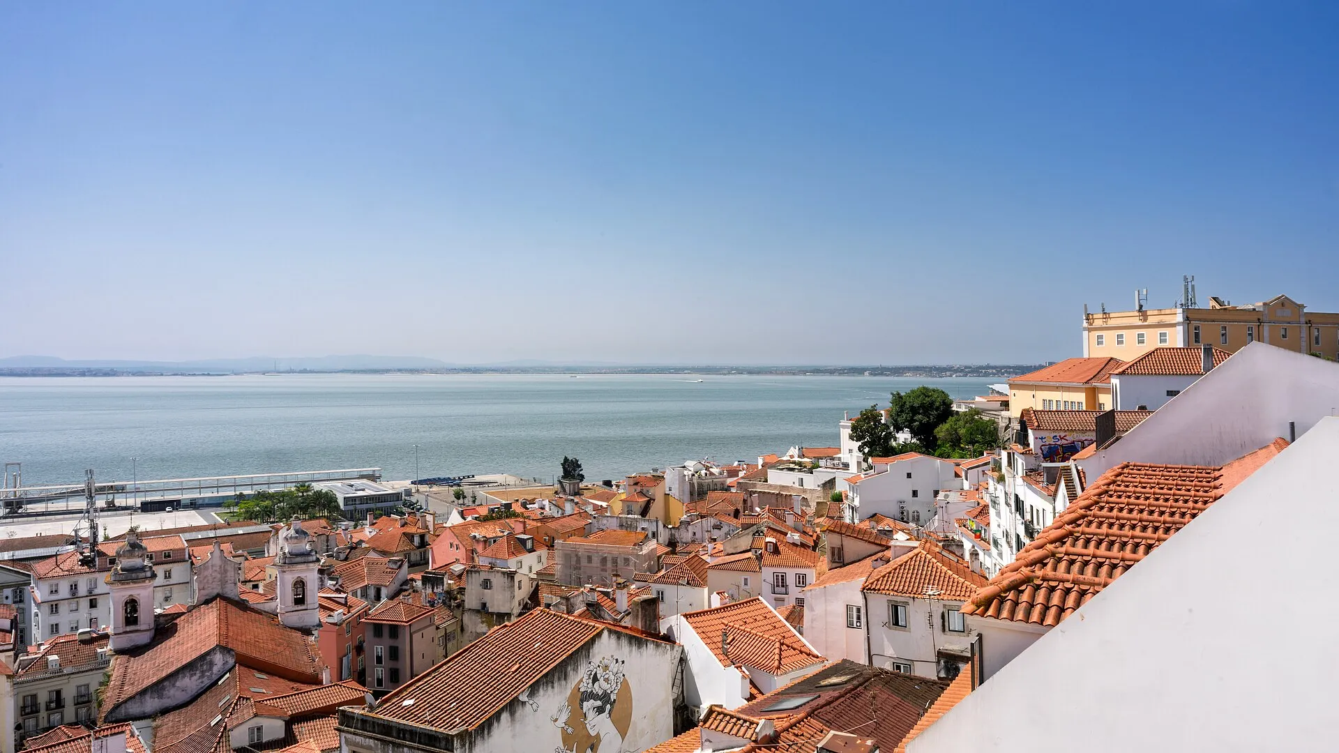 Terracotta rooftops of Lisbon stretching down to the Tagus river